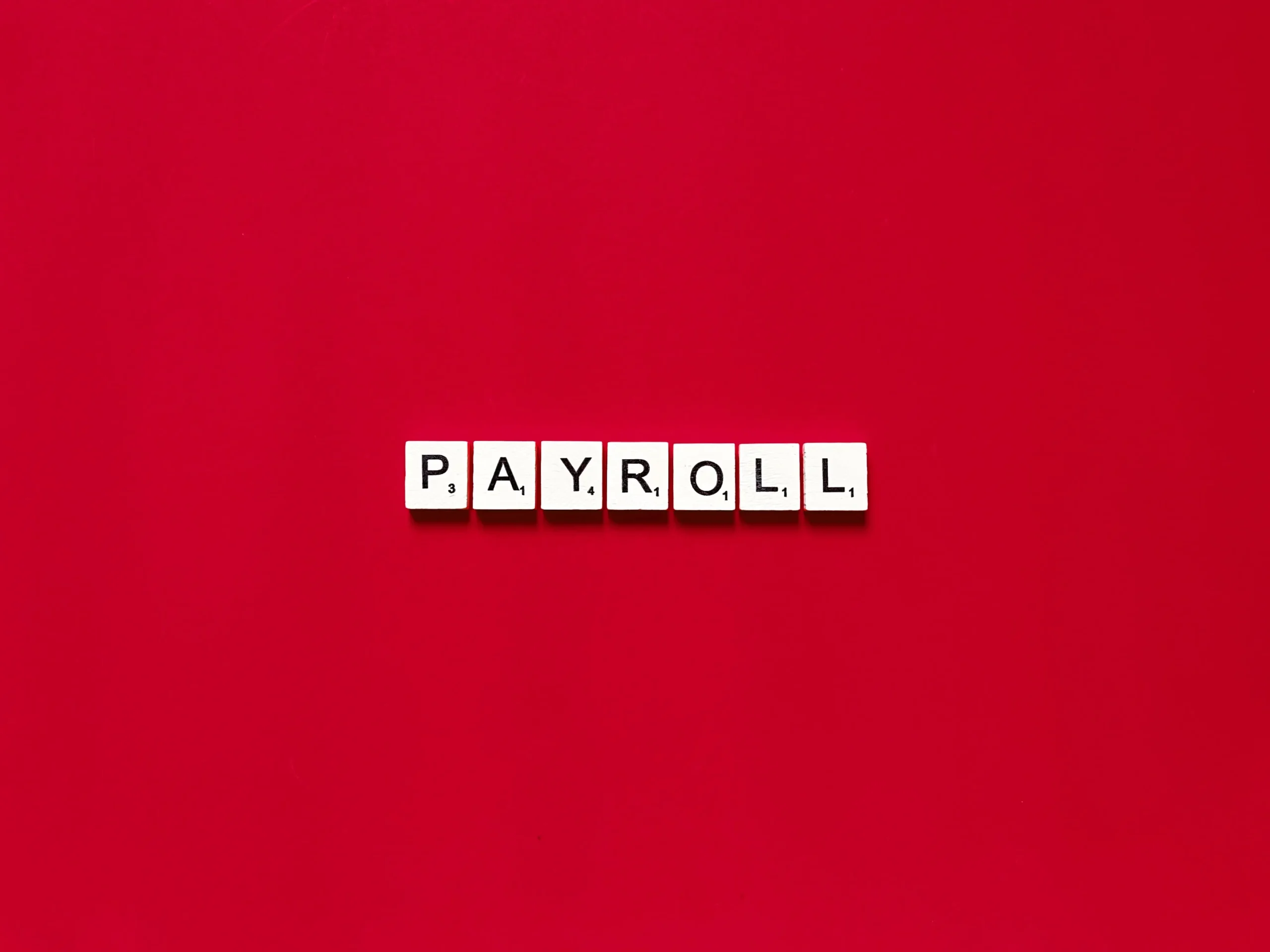 payroll spelled out with letter tiles on red